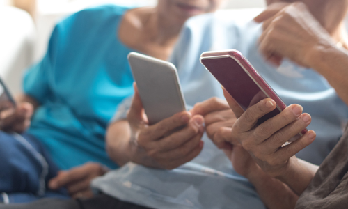 Three people sat on a sofa with mobile phones