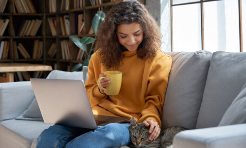 Women sitting on the sofa smiling and stroking her cat