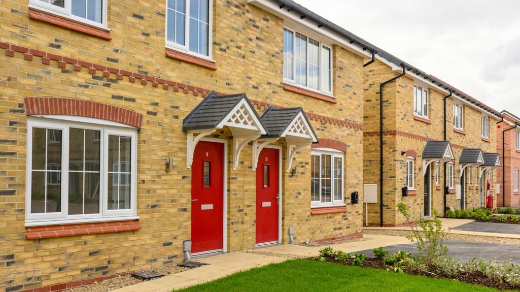 The front of two adjoining brick houses with red doors