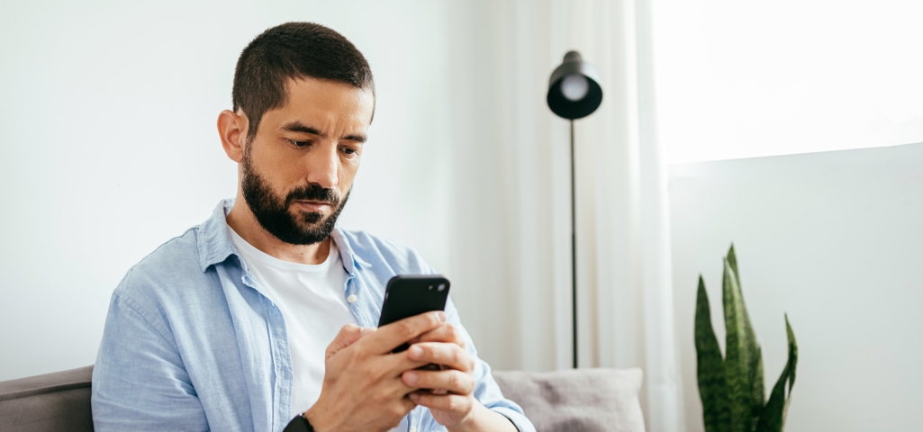 Man sat on the sofa looking at phone screen