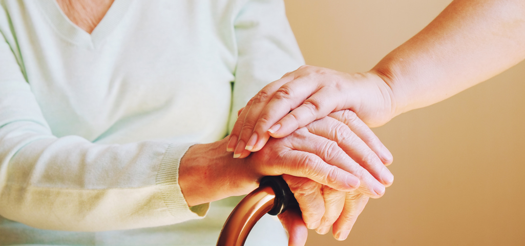 Picture of a senior woman with her caregiver holding a stick