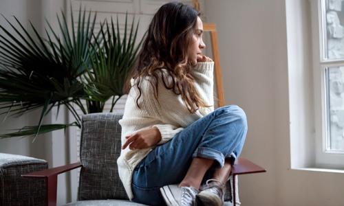 Young woman sat on a chair looking out of the window