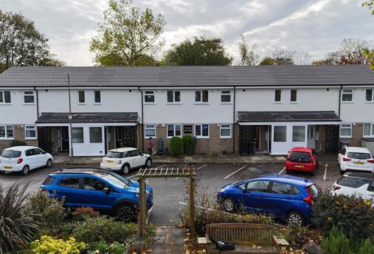 Front view of refurbished flats at Allen Croft with new windows, clean external finishes and parked cars 