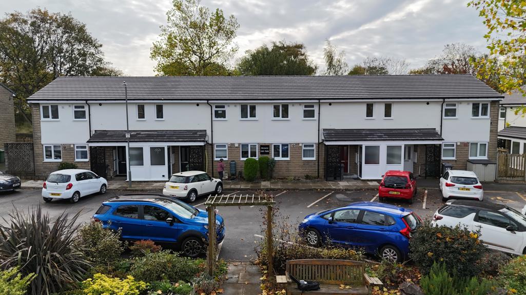 Front view of refurbished flats at Allen Croft with new windows, clean external finishes and parked cars 