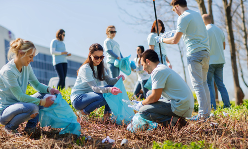 group of volunteers with garbage bags cleaning area in park