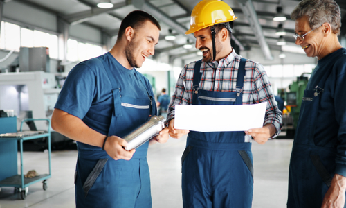 Three men stood in a warehouse wearing overalls