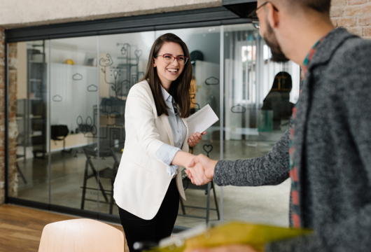 Man and woman shaking hands in a modern office.