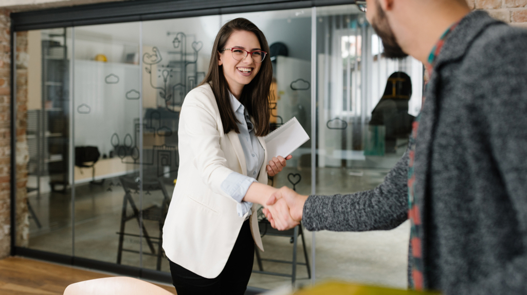 Man and woman shaking hands in a modern office.