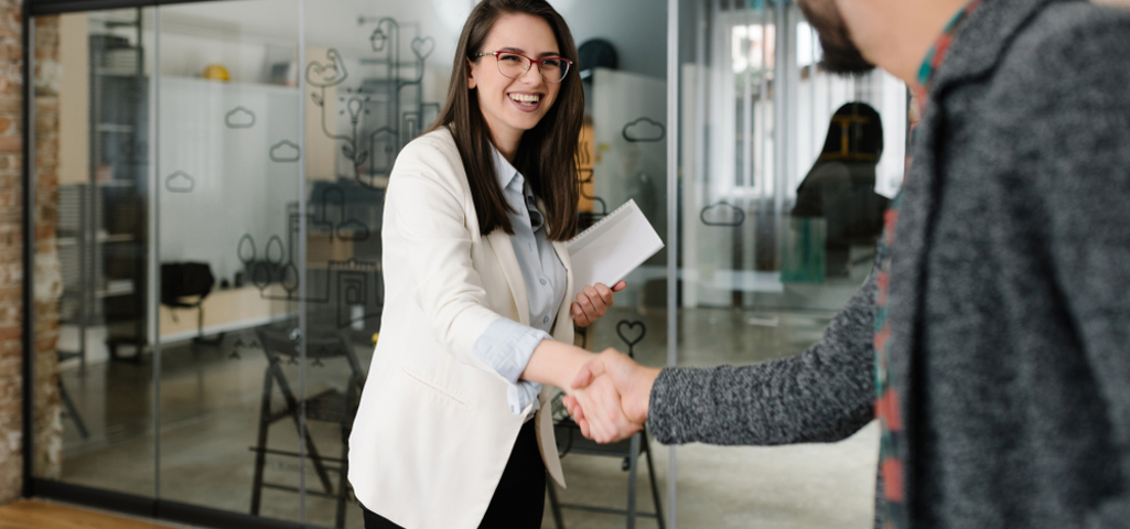 Man and woman shaking hands in a modern office.