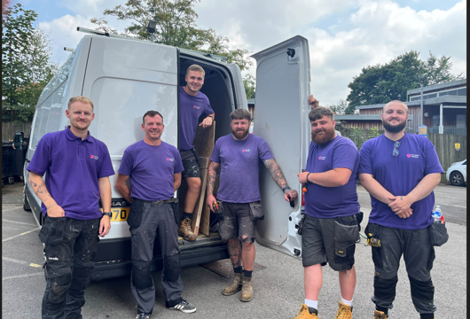 Yorkshire Housing maintenance team of six men smiling beside a white van
