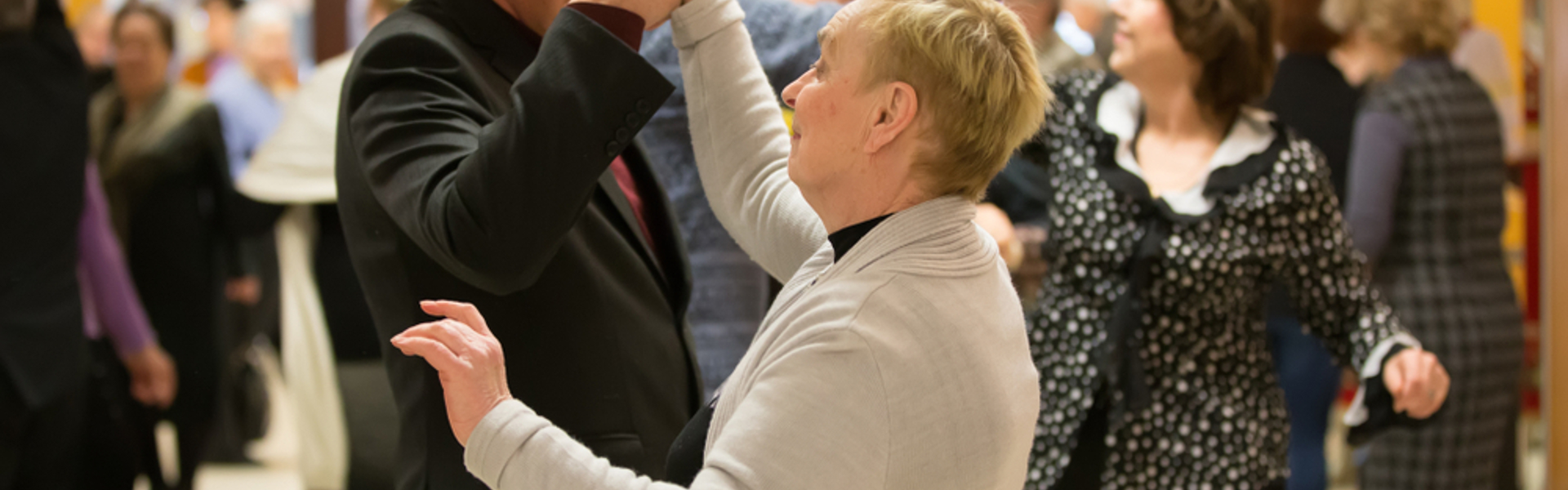 Two older people dancing together in a room 