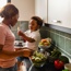 A woman cooking in the kitchen with a young child