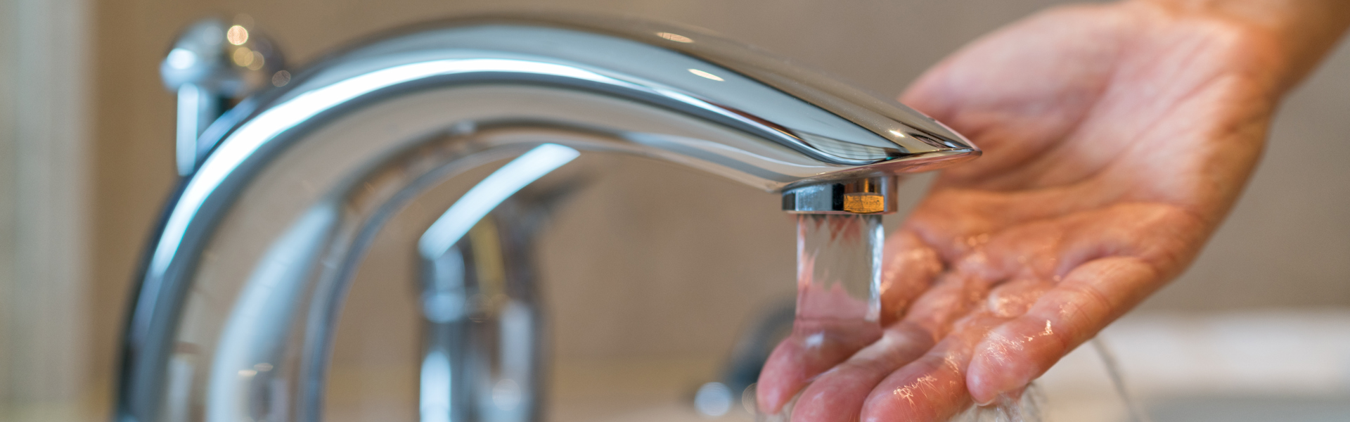 Tap running with a hand testing temperature of the water