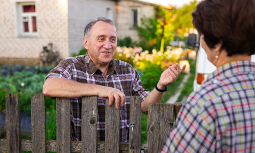 Picture of an older man speaking to someone over a garden fence