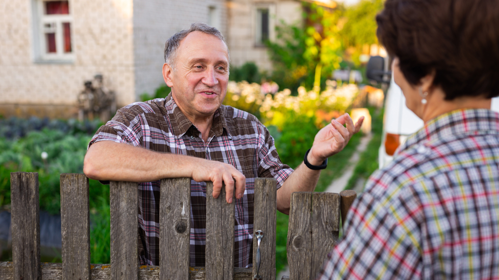 Picture of an older man speaking to someone over a garden fence