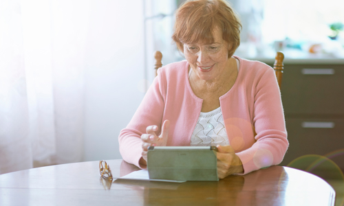 Woman sat at a table on an iPad