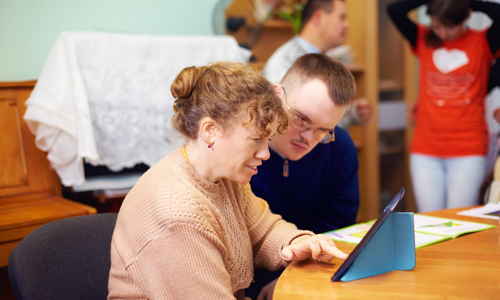 Man and woman sat at a table using an iPad
