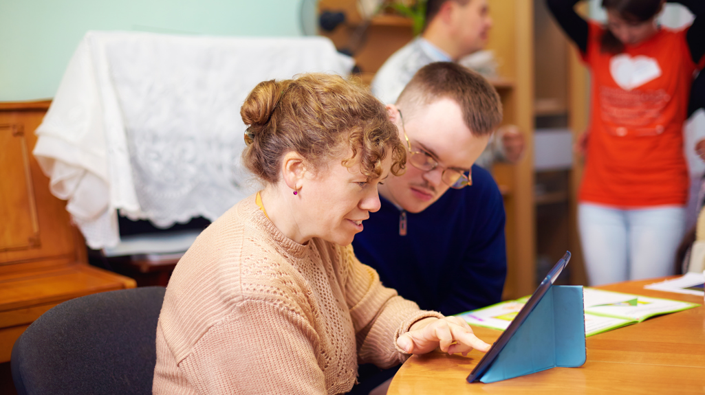Man and woman sat at a table using an iPad