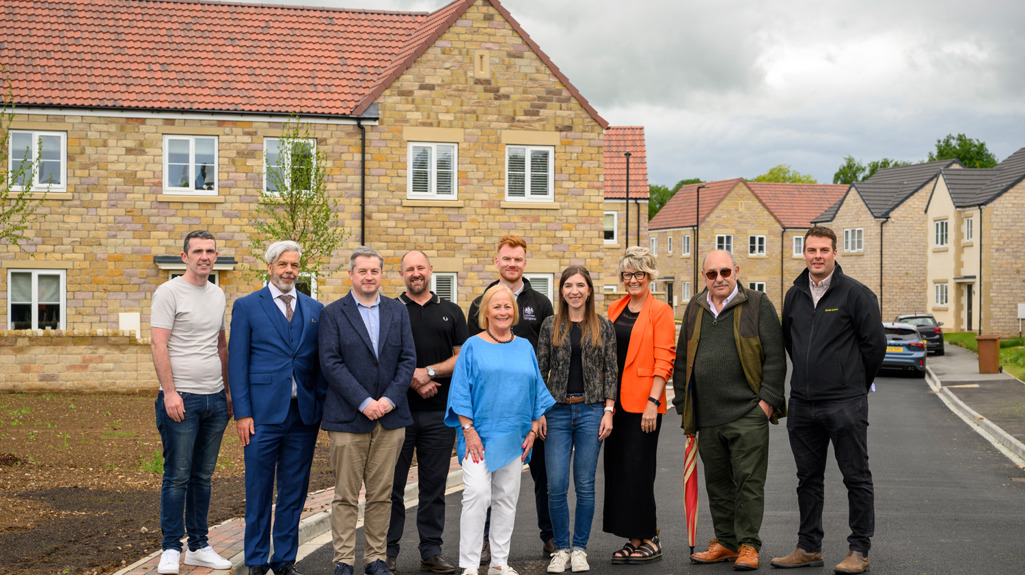 Yorkshire Housing colleagues, contractors, councillors, and residents posing for a photo at the entrance of the Bridgewell development.