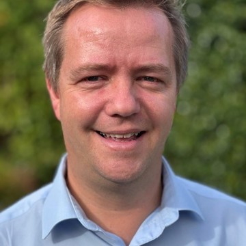 Man in blue shirt smiling at the camera 
