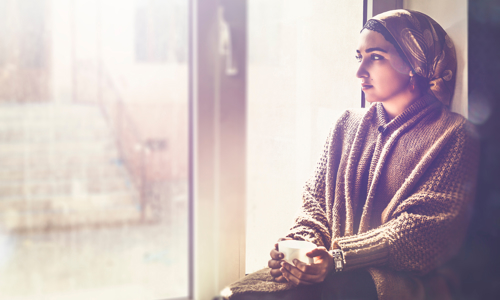 Person sat on a window ledge with a cup of tea.