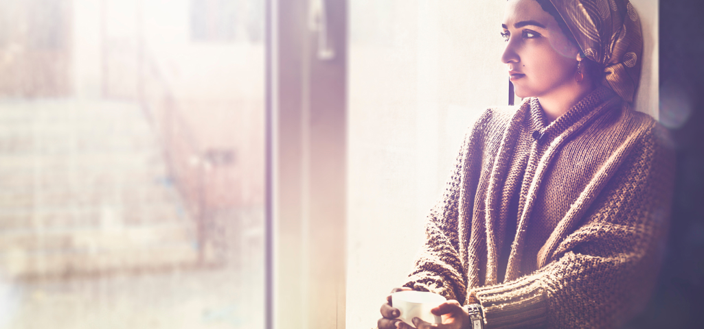 Person sat on a window ledge with a cup of tea.