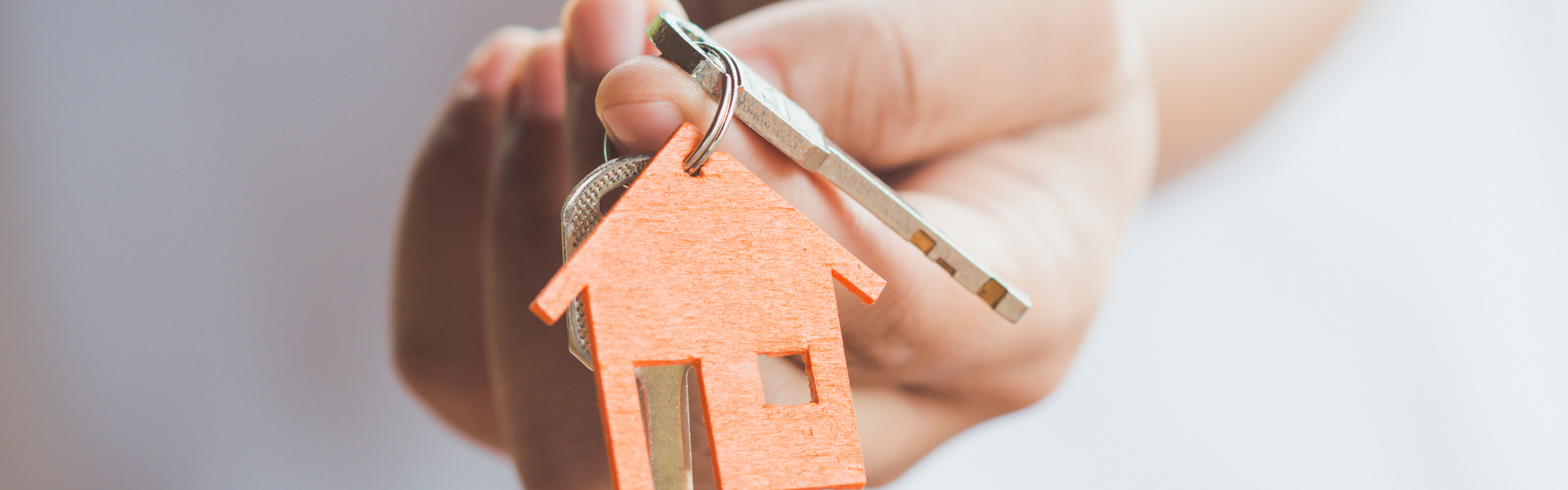 Person holding out a set of house keys.