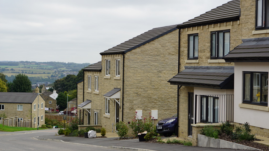 Houses at Cromwell Gardens down a hill with a view down the valley in the background